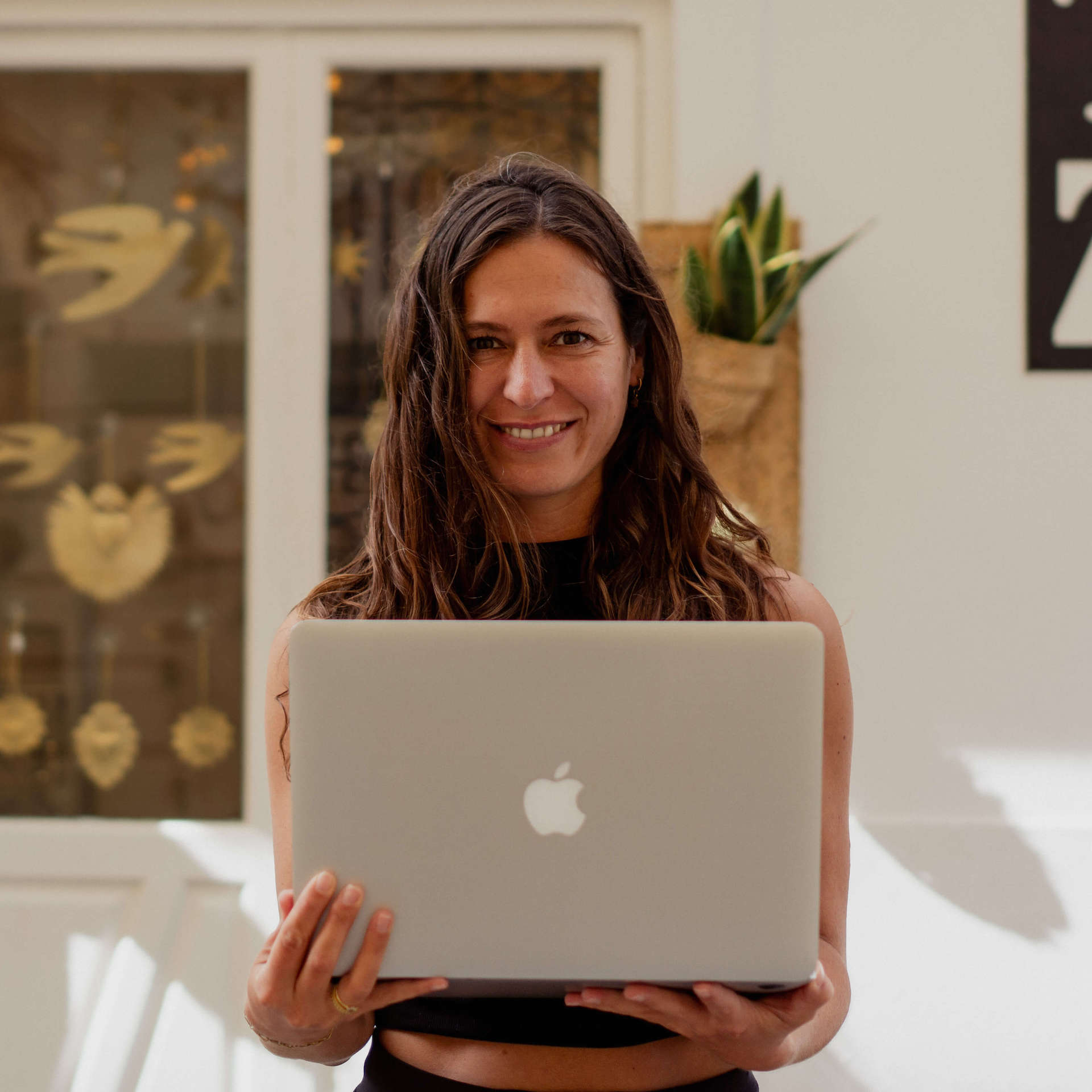 Wordpress Webdesignerin Melanie Aurich hält ihren MacBook vor sich und lächelt in die Kamera