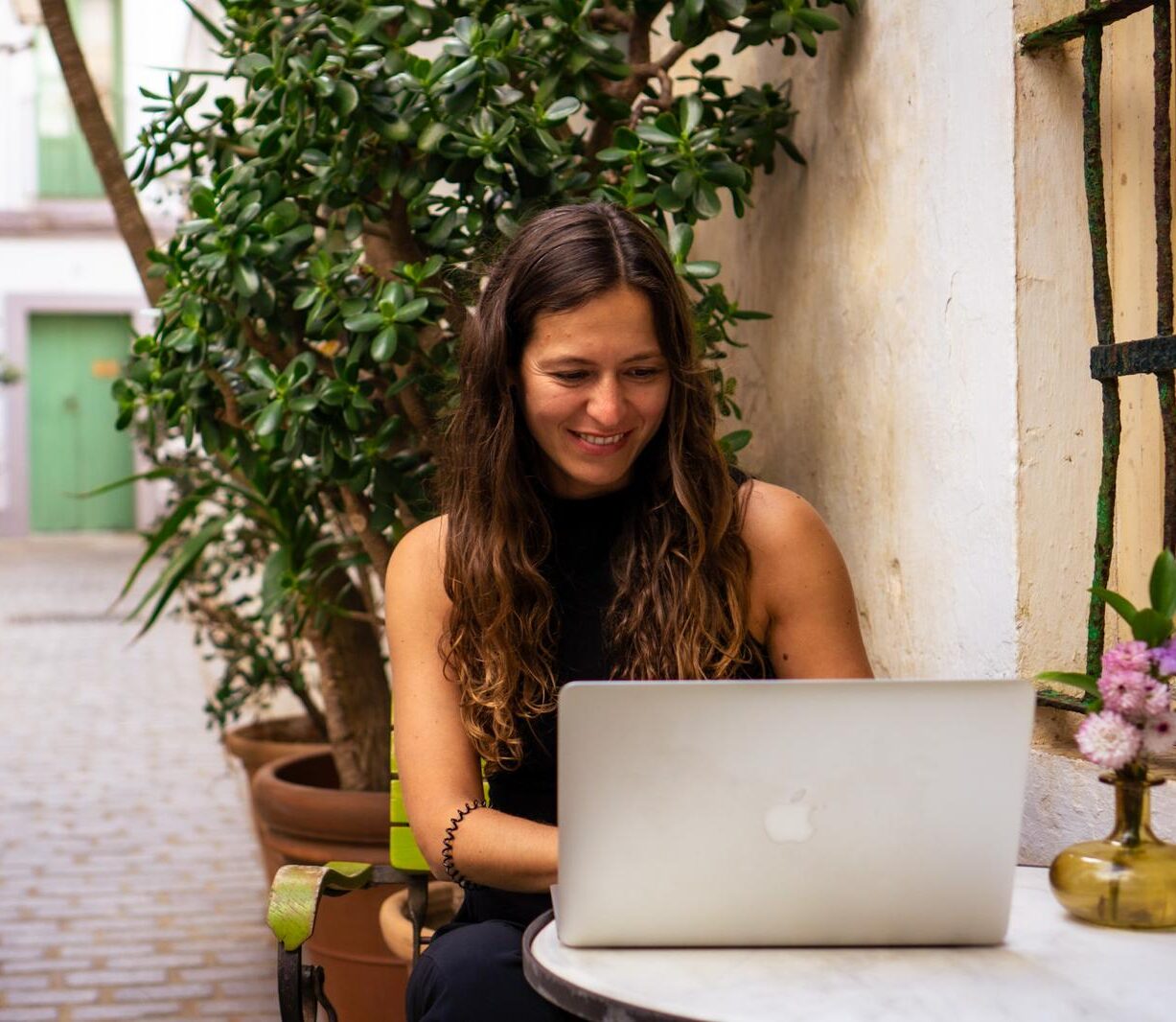 Wordpress Webdesignerin Melanie Aurich sitzt vor ihrem MacBook und lächelt